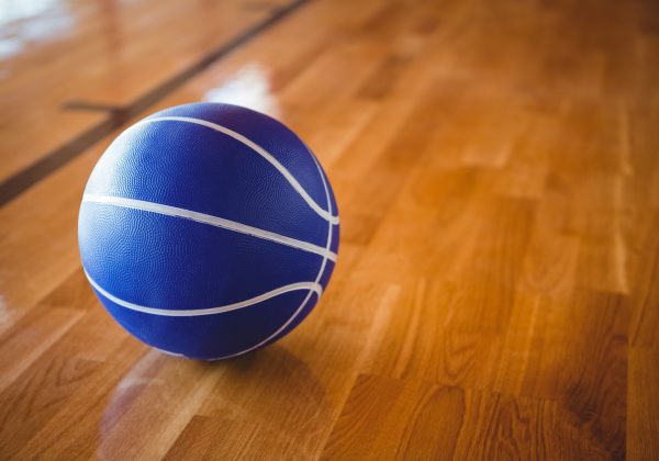 Close up of blue basketball on hardwood floor in court